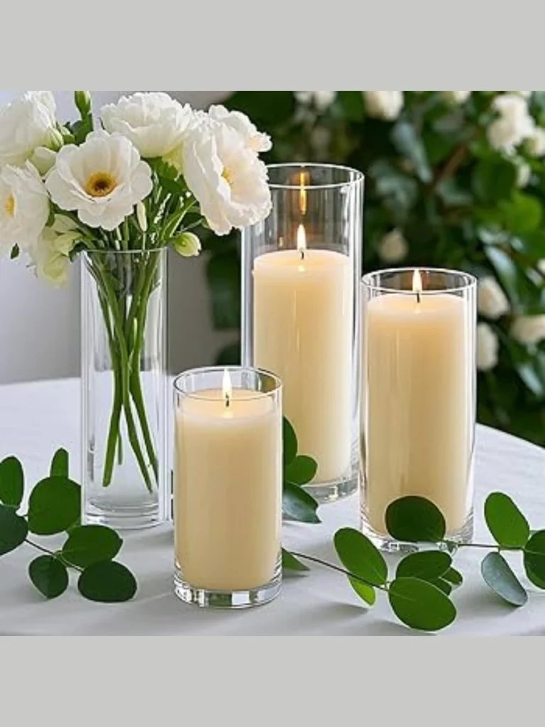 Position three White Pillar Candles Inside Tall Glass Hurricane Sleeves Surrounded by Fine Sea Sand